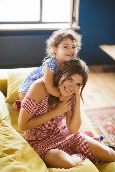 Siyah kıvırcık saçlı sarılmakla neşeli bebek kız anne mutlu kamera birlikte kanepede evde vakit arıyorsunuz 