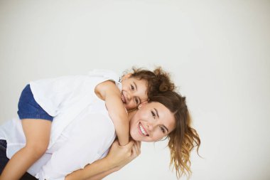 Neşeli anne küçük gülümseyen kızı sevinçle kamera birlikte beyaz arka plan üzerinde arıyorsunuz geri tutarak