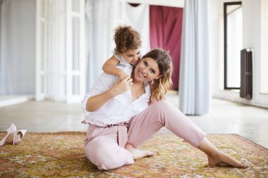 Küçük güzel kızım mutlu seyir fotoğraf makinesindeki harcama zaman birlikte evde halı üzerinde geri tutan genç neşeli anne