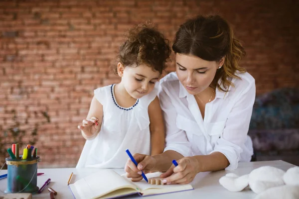 Güzel genç anne ve bebek kızı sersem Not Defteri'nde keçeli kalemler ile birlikte rahat ev, çizim