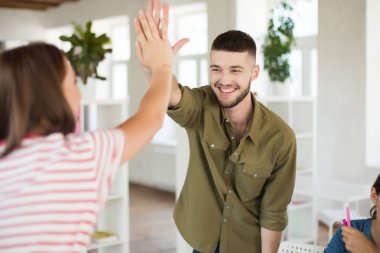 Mutlu kız ofiste yüksek beş hareket veren gömlekli sakallı genç gülümseyen adam