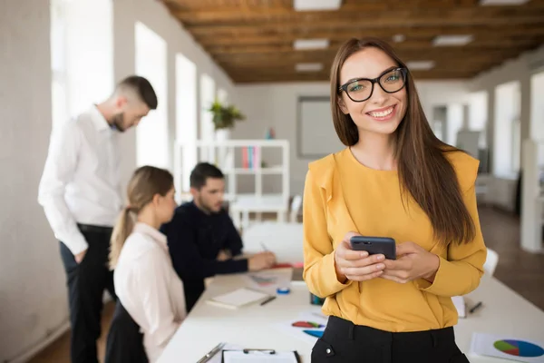 Genç Kadını Mutlu Kamera Tutarak Cep Telefonu Elinde Office Meslektaşları — Stok fotoğraf