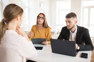 Düşünceli bir kenara gözlük kadında iş yaparken klasöre el ile başvuru çalışmaları hakkında konuşurken seyir ile dizüstü bilgisayar ile iş adamı. Genç işverenler iş harcamaları modern ofiste röportaj