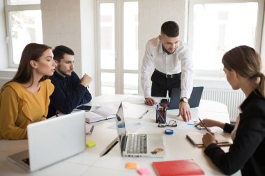 Yaratıcı insanların laptop ve Not defteri ile birlikte çalışma grubu. Yeni Proje modern ofiste vakit üzerinde kadın ve genç iş adamları 