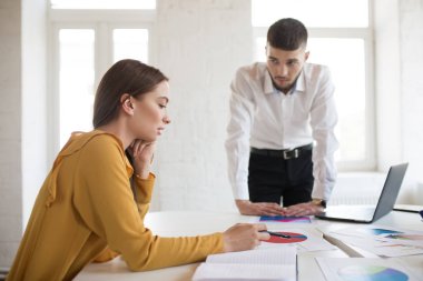 Düşünceli çalışan arıyorsunuz masada yaslanmış beyaz gömlekli genç erkek patron. Güzel kız bluz modern ofis diyagramları ile çalışma