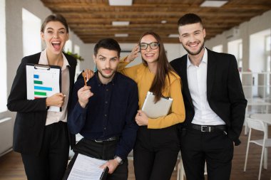 Neşeli yaratıcı insanların mutlu bir şekilde kamera modern ofiste vakit birlikte arıyor takım elbiseli Grup 