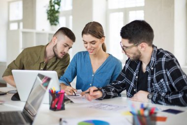 Yaratıcı gençlerin yeni projede birlikte çalışan dizüstü bilgisayar ile. Neşeli işçilerin vakit modern ofiste Grup