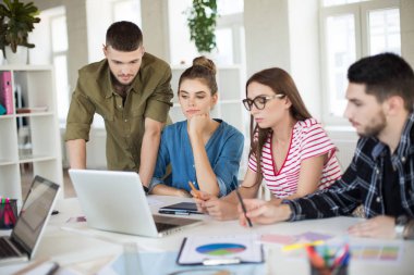 Genç iş insanlar düşünceli dizüstü bilgisayarda birlikte çalışıyor. Grup düşünceli erkek ve kadınların iş yerinizde modern ofis vakit