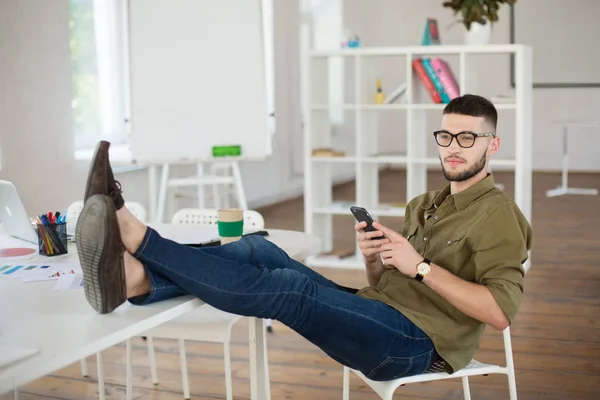 Junger Mann Mit Brille Und Hemd Handy Auf Stuhl Sitzend — Stockfoto