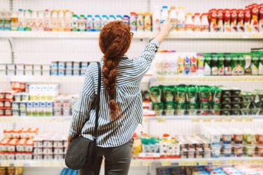 Süt ve süt ürünleri modern süpermarkette seçme arkadan çizgili gömlekli güzel kız