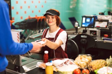 Mutlu bir şekilde modern süpermarkette çalışma üniforma çok gülümseyen kadın kasiyer