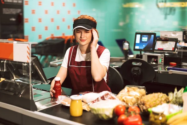 Jonge Vrouwelijke Caissière Uniform Met Hoofdpijn Werken Moderne Supermarkt — Stockfoto