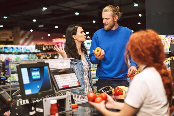 Young Couple Standing Cashier Desk Emotionally Discussing Something Buying Products — Stock Photo, Image