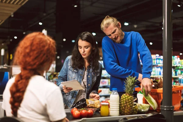 Ung Kvinna Med Shopping Lista Står Nära Kassan Skrivbord Medan — Stockfoto