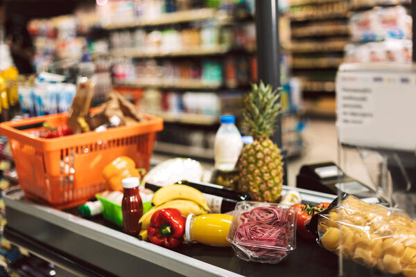 Close up shopping basket and fresh products on cashier desk in modern supermarket