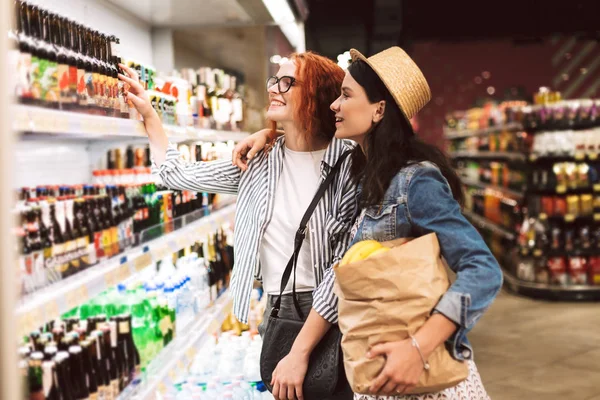 漂亮的女孩与纸杂货袋充满产品快乐地选择现代超市的产品 — 图库照片