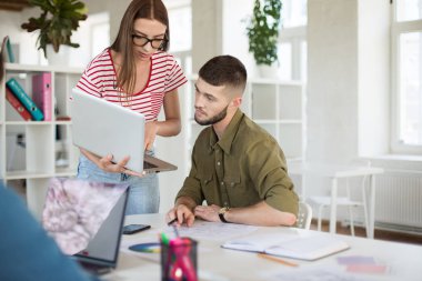Düşünceli genç gömlek ve çizgili tişört ve düşünceli dizüstü bilgisayar ile birlikte çalışma gözlük kadında. İş adamları, vakit modern ofis iş