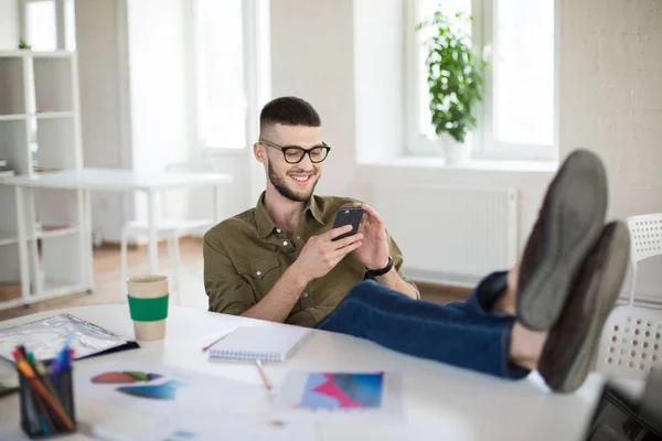 Joven Hombre Sonriente Gafas Camisa Felizmente Usando Teléfono Celular Sentado — Foto de Stock