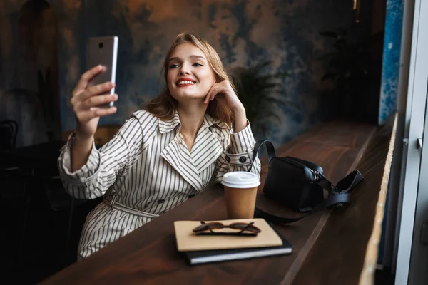 Ganska Leende Flicka Randig Trenchcoat Med Glädje Foton Mobiltelefon Med — Stockfoto