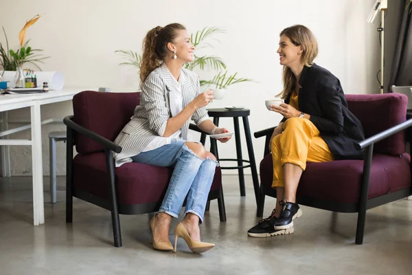 Duas Belas Mulheres Elegantes Alegremente Falando Segurando Xícaras Café Mãos — Fotografia de Stock