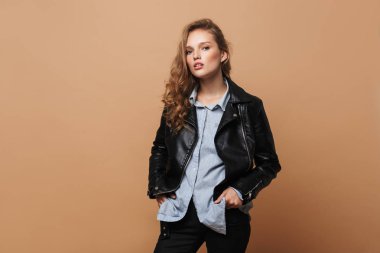 Ceplerinde düşünceli kamera seyir bej renkli arka plan üzerinde siyah deri ceket ve gömlek holding dalgalı saçlı Genç güzel kadın eller