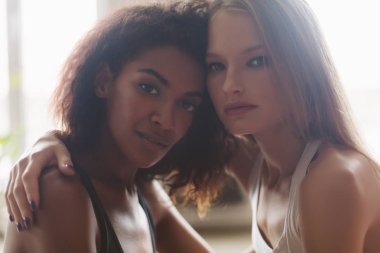 Siyah kıvırcık saçlı Genç güzel bir Afrikalı-Amerikalı kadın ve sersem birlikte kamera seyir sarışın saçlı güzel kadın portre