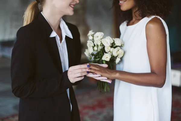 黒のスーツで白人女性と結婚式でお互いの手を繋いでいる小さな花束と白いドレスのアフリカ系アメリカ人女性を閉じる — ストック写真