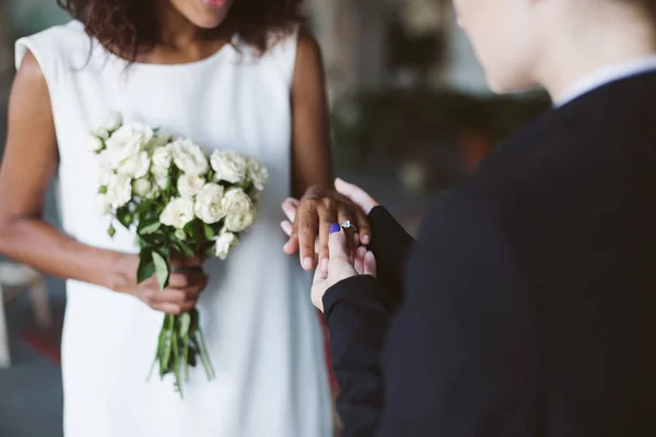 关闭妇女在黑色西装把结婚戒指上美丽的非洲裔美国人妇女在白色礼服婚礼仪式上 — 图库照片