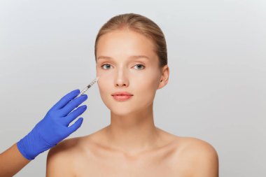 Güzellik enjeksiyon sersem kamera seyir gri arka plan üzerinde şırınga ile göz alan içinde getting genç güzel kadın portresi