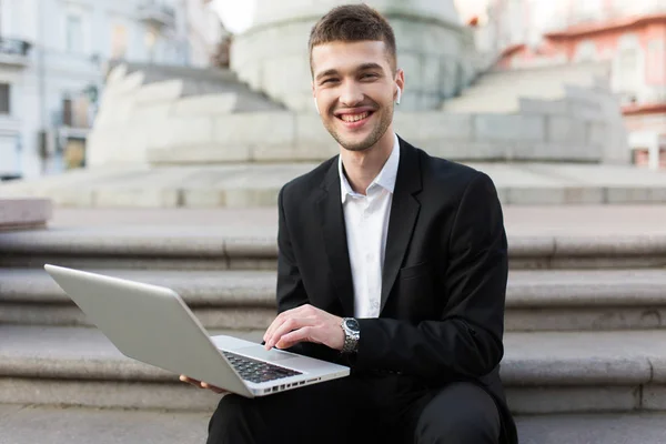 Joven Hombre Negocios Sonriente Traje Negro Clásico Con Auriculares Inalámbricos — Foto de Stock