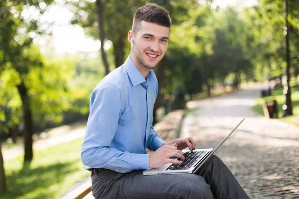 Joven Hombre Sonriente Camisa Azul Con Auriculares Inalámbricos Sentado Banco — Foto de Stock