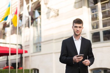 Siyah takım elbiseli, beyaz gömlekli, kablosuz kulaklıklı, elinde cep telefonu olan genç yakışıklı bir adam rüyamda kameraya bakıyordu.