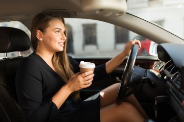 Kahve sersem elinde tutan arabayı direksiyonuna oturan siyah elbiseli Genç güzel kadın düz seyir