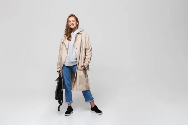 Ung Smilende Kvinde Skyttegrav Frakke Jeans Holder Sort Rygsæk Hånden - Stock-foto