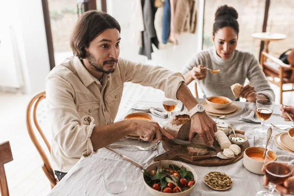 Hombre Guapo Con Cabello Oscuro Barba Sentado Mesa Cortando Pan — Foto de Stock