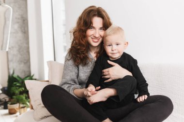 Kanepeye onunla kamera birlikte mutlu bir şekilde seyir biraz yakışıklı oğlu oturan genç oldukça gülümseyen kadın. Sersem evde rahat oturma odasında vakit erkek bebek ile anne