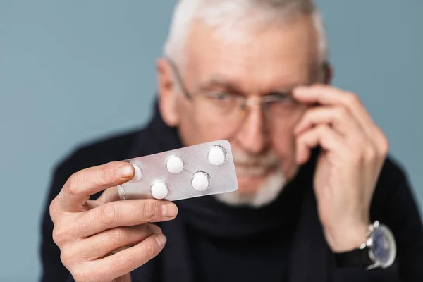 Close up old man in eyeglasses and scarf thoughtfully holding pi