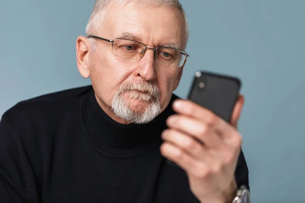 Old pensive man with gray hair and beard in eyeglasses and sweat