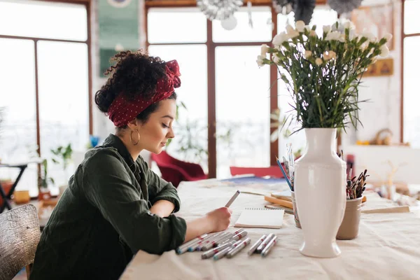 Young beautiful woman with dark curly hair sitting at the table — Stock Photo, Image