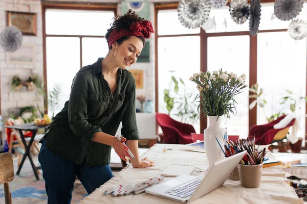 Young gorgeous smiling woman with dark curly hair leaning on tab — Stock Photo, Image