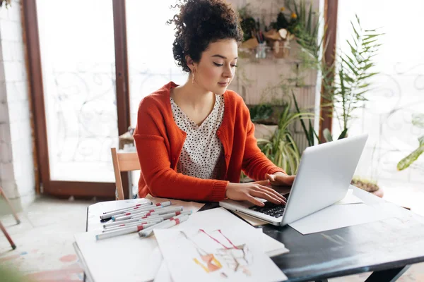 Young beautiful woman with dark curly hair sitting at the table — Stock Photo, Image