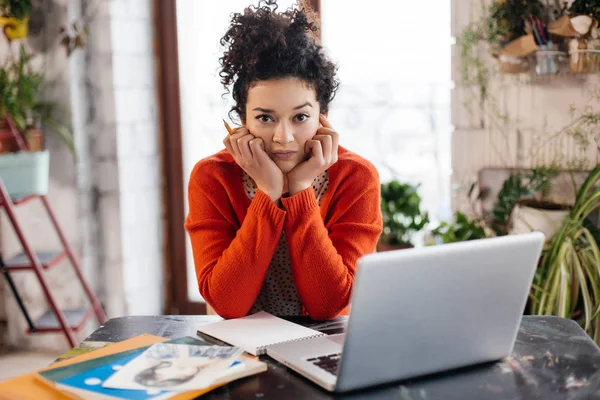 Junge ernste Frau mit dunklem lockigem Haar am Tisch sitzend le — Stockfoto