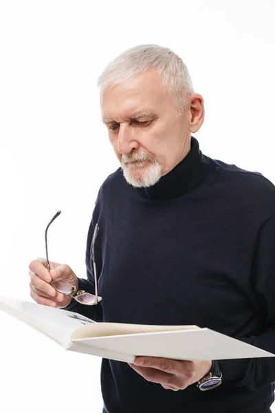 Old handsome man with gray hair and beard in black sweater holdi — Stock Photo, Image