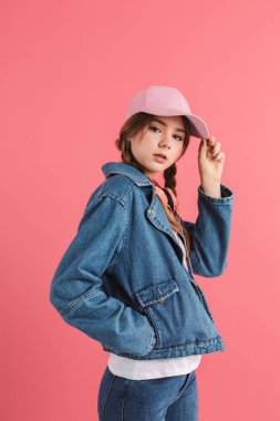Young attractive girl with two braids in denim jacket and cap wi