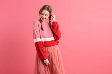 Young beautiful smiling girl with two braids in sweater and long