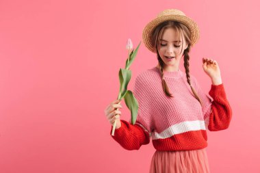 Young pretty girl with two braids in sweater and straw hat holdi