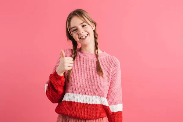 Jong vrolijk meisje met twee vlechten in trui tonen duim omhoog — Stockfoto