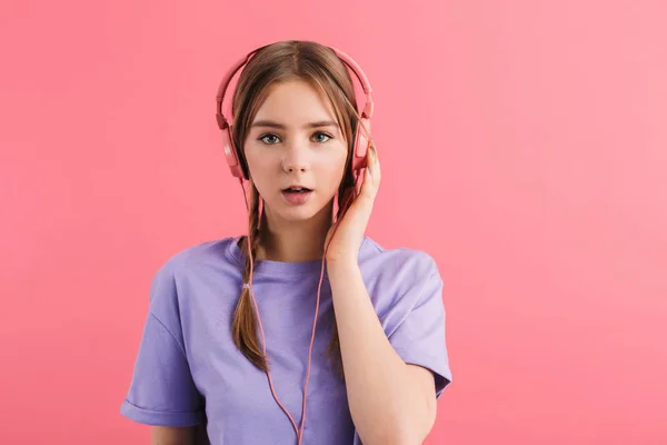 Nuori hämmästynyt tyttö, jolla on kaksi punokset lila t paita kuuntelu — kuvapankkivalokuva
