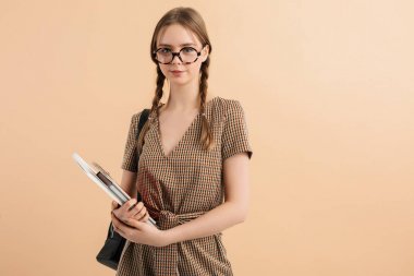 Yünlü tulum ve gözlüklü iki örgülü gülümseyen genç bayan.