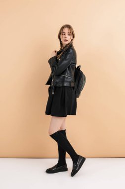 Deri ceketli ve etekli iki örgülü hayalperest kız.